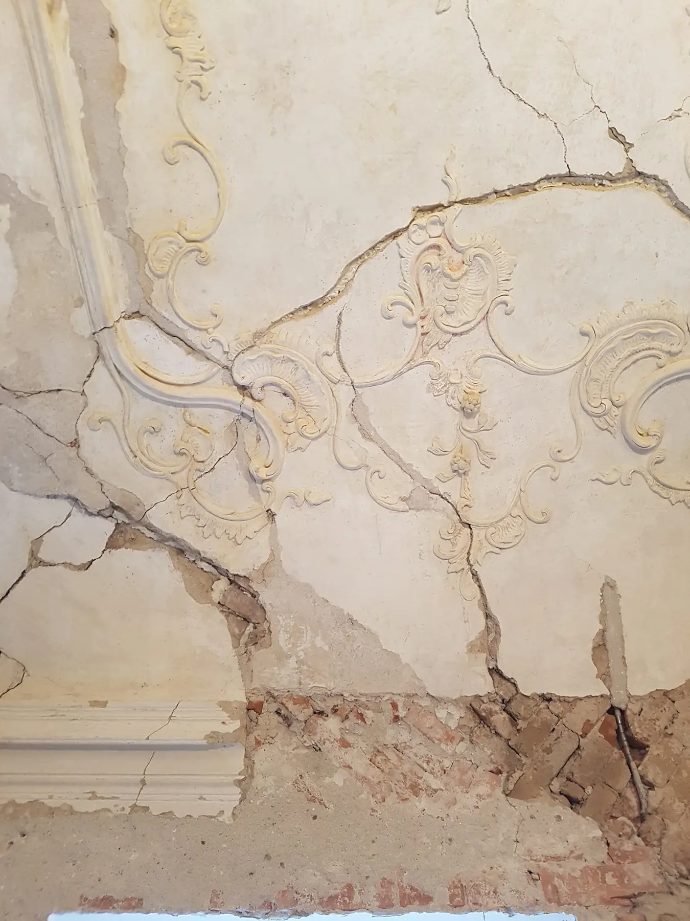 Poškodená štuková ornamentika a odpadnutá omietka