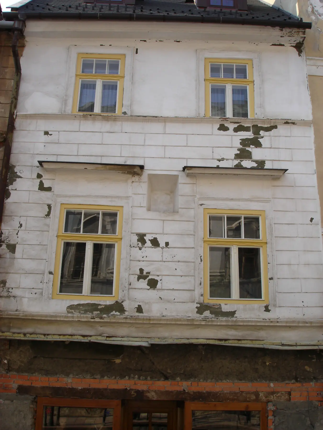Fasáda pred obnovou s opadanou omietkou
